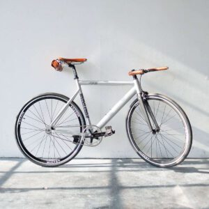 A bicycle is parked against the wall in front of a white wall.